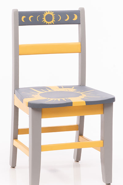 Grey and black chair with yellow. It has three hands holding a solar eclipse. 