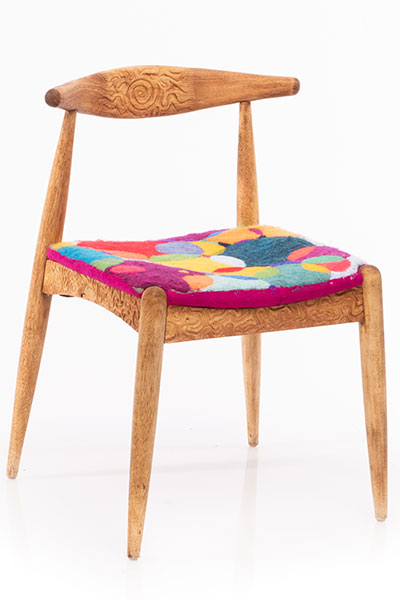 the seat has bright colored overlapping circles and the frame has swirls carved into it. 