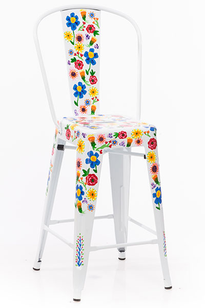 A tall metal white chair with painted flowers, great for a craft room.