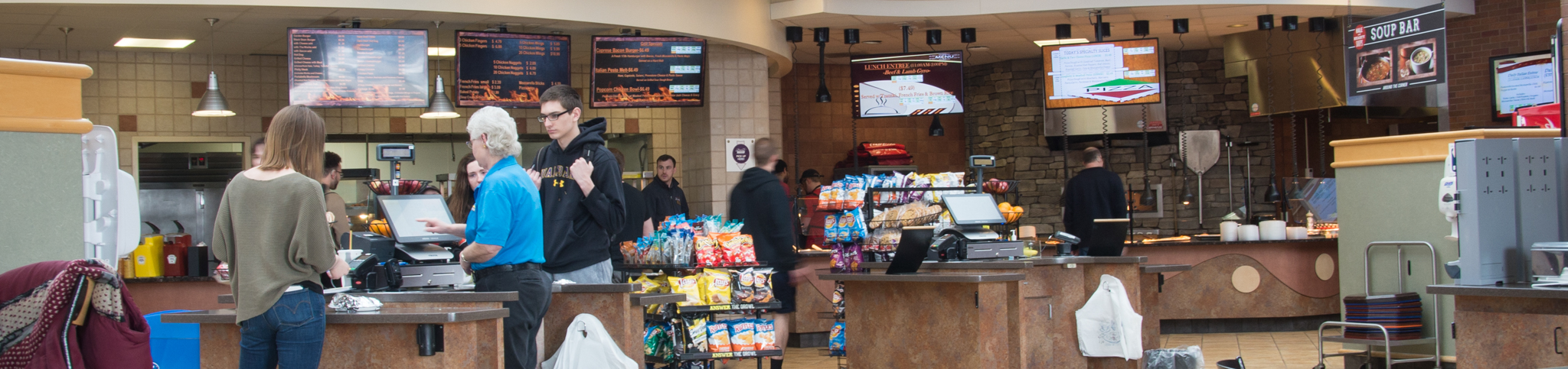 cashier at desk with stations of food in background