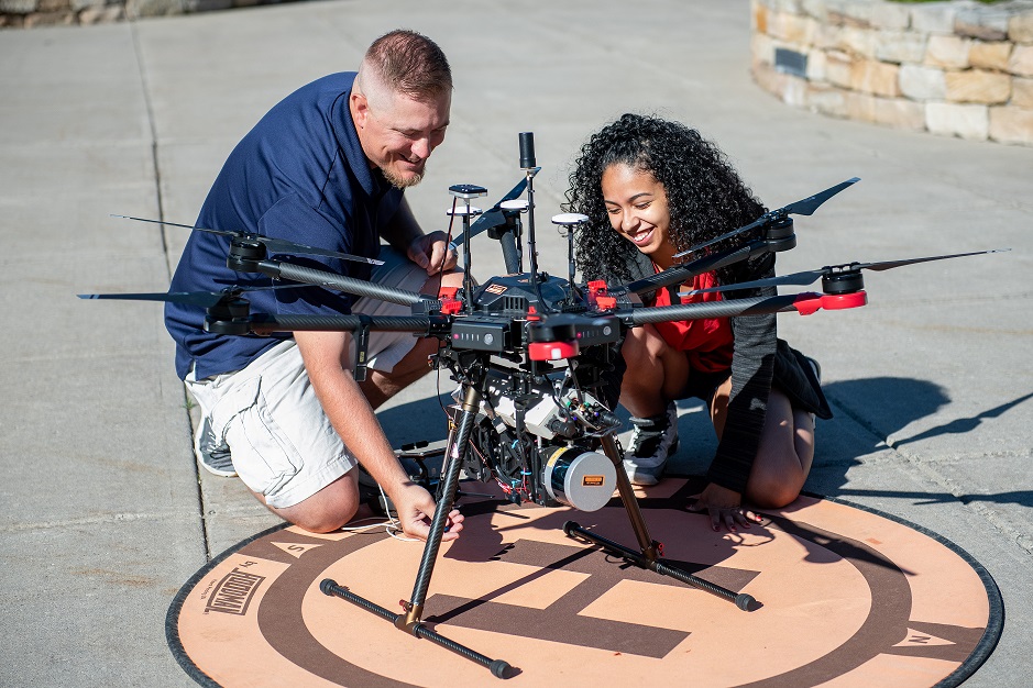 2 people working with a large drone.