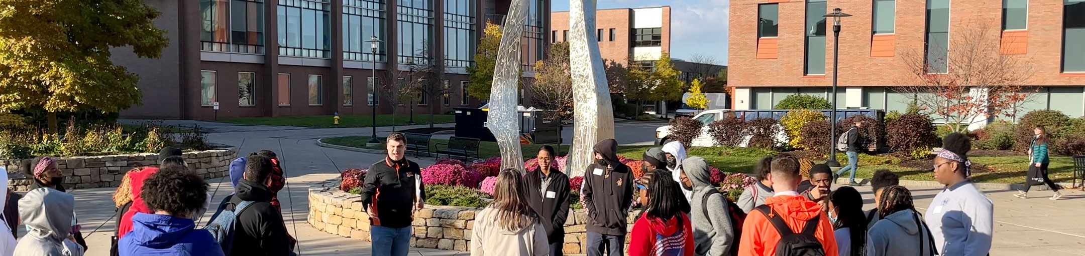 a group of students outside in front of an art sculpture