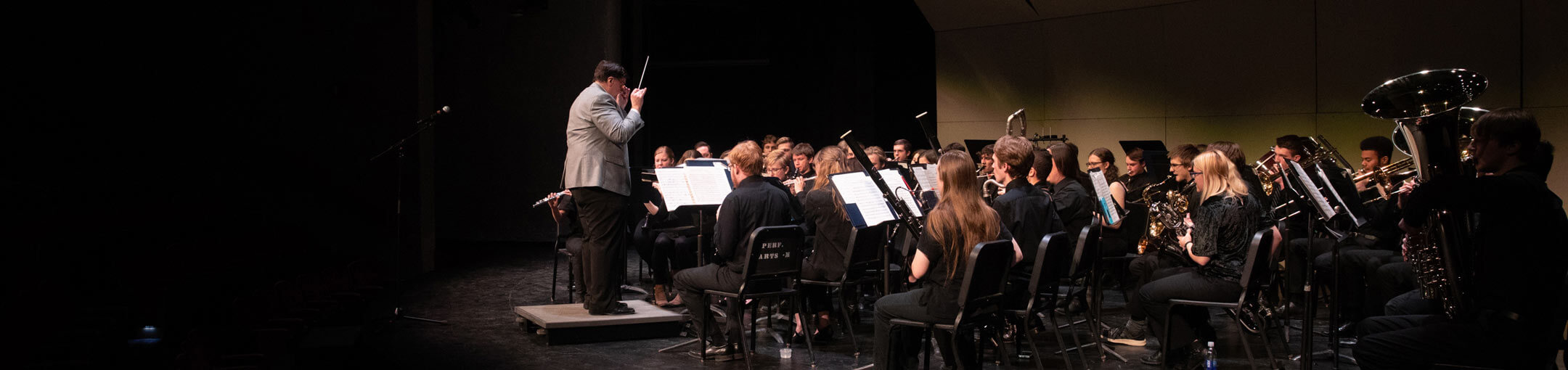 A music director conducting a piece of music played by the RIT Concert Band.