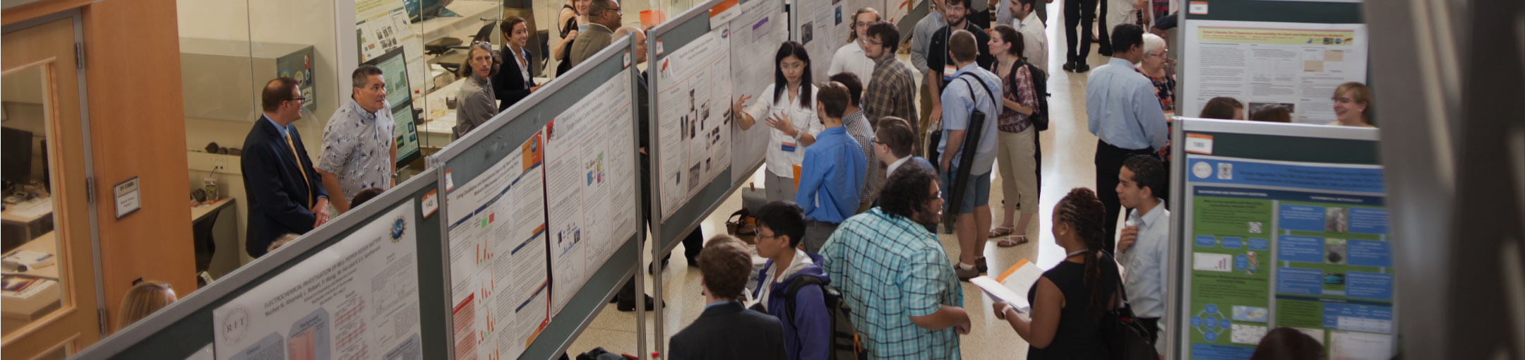 Participants and attendees of a previous Undergraduate Research Symposium viewing various exhibits.