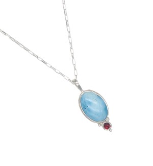 a pendant with a pale blue hued turquoise bezel set in Sterling and accentuated with a pop of color compliments of a ruby garnet.