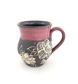 a ceramic mug with dark clay body illustrated with roses and glazed in a rose hued glaze at the rim and handle.