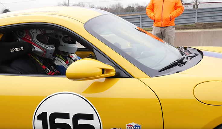 2 people sitting in a yellow Porsche race car