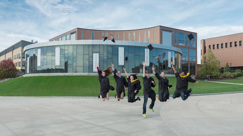 Students all jumping at once in front of a building