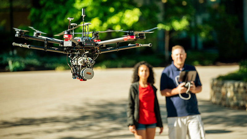 a drone with 2 people behind it out of focus