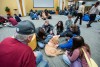 group of students sitting in a circle on the floor petting a golden doodle dog.