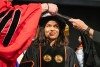 a college age woman is shown recieving a Ph.D. hood at the 2024 commencement.