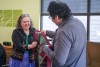 an older female accepts a purple and green native american blanket from an older male.