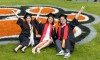 Three students pose for a photo outside the Gordon Field House following commencement.