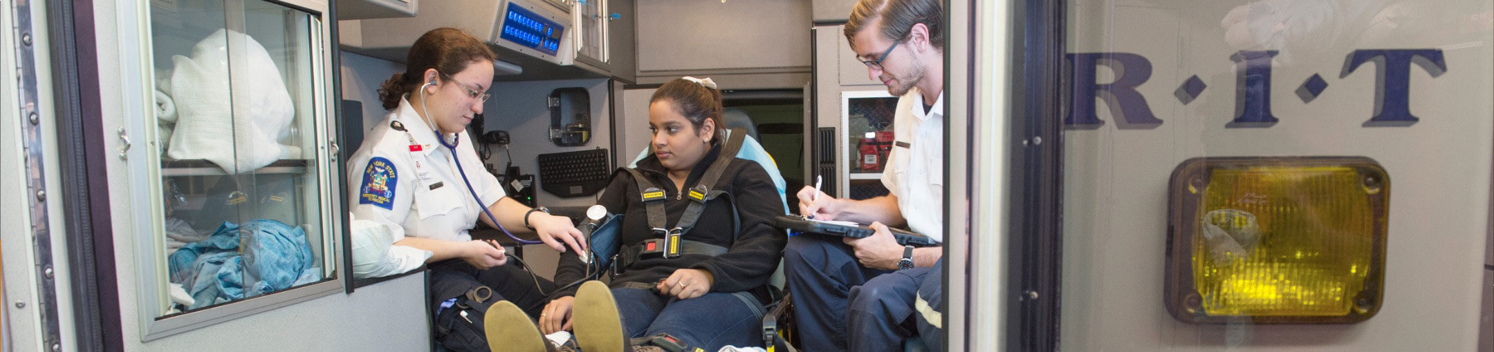 A person in the back of an ambulance with two health professionals.