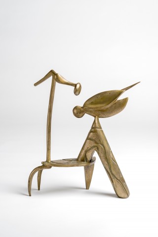 Bronze standing sculpture with four legs that support a pod-like head shape and a tall antennae like shape