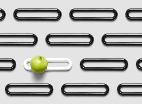 Series of white and black elongated loops arranged in rows with a single green apple