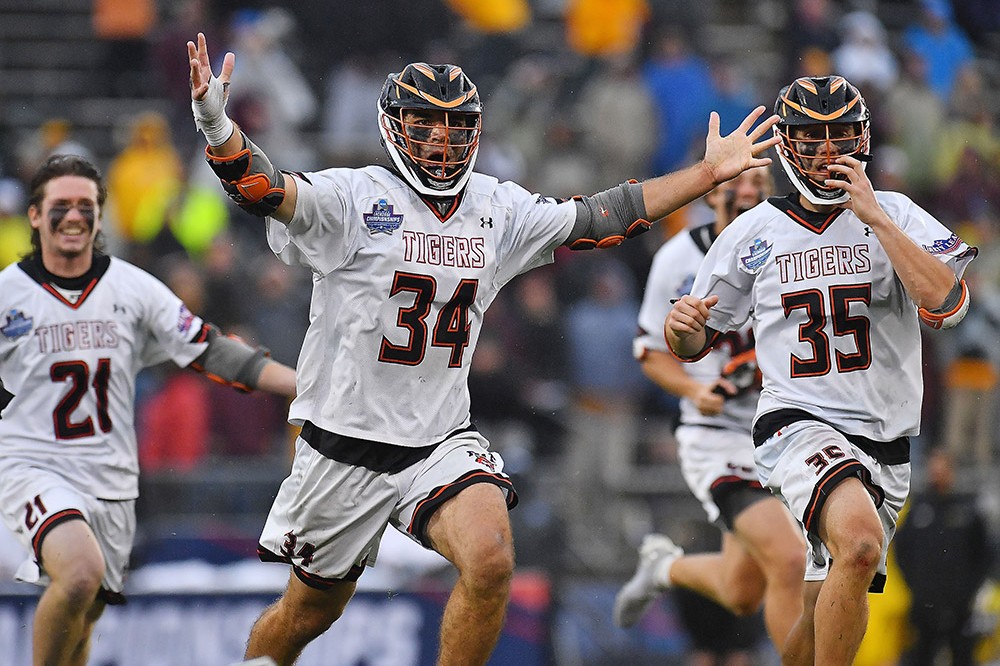 three men's lacrosse players celebrate a goal.