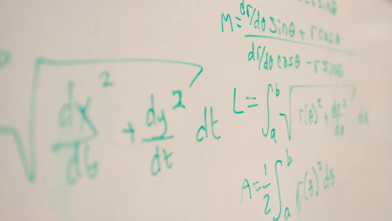 A whiteboard with multiple equations written on it in green marker.