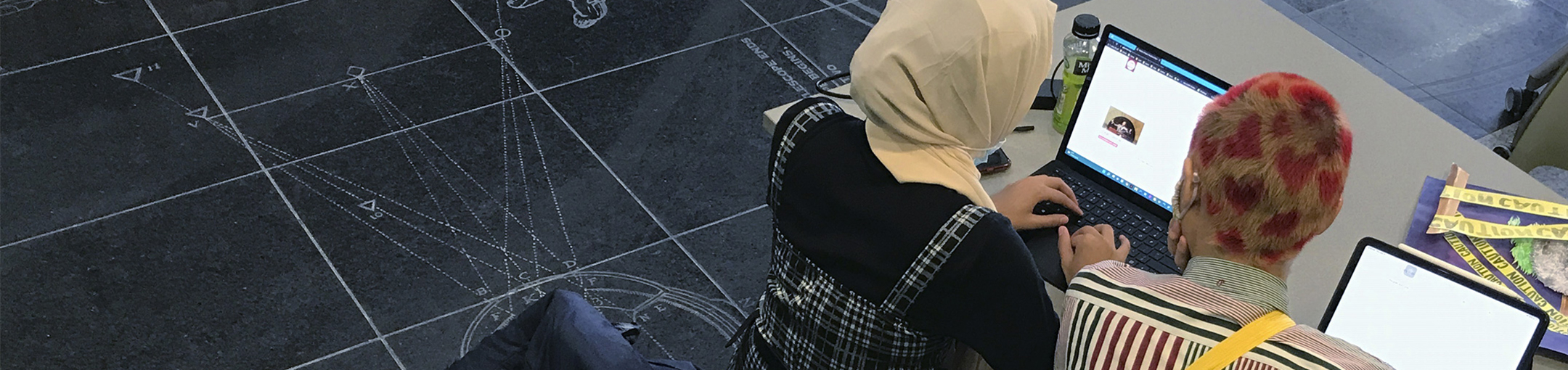 The back of two students' heads looking at computer screens