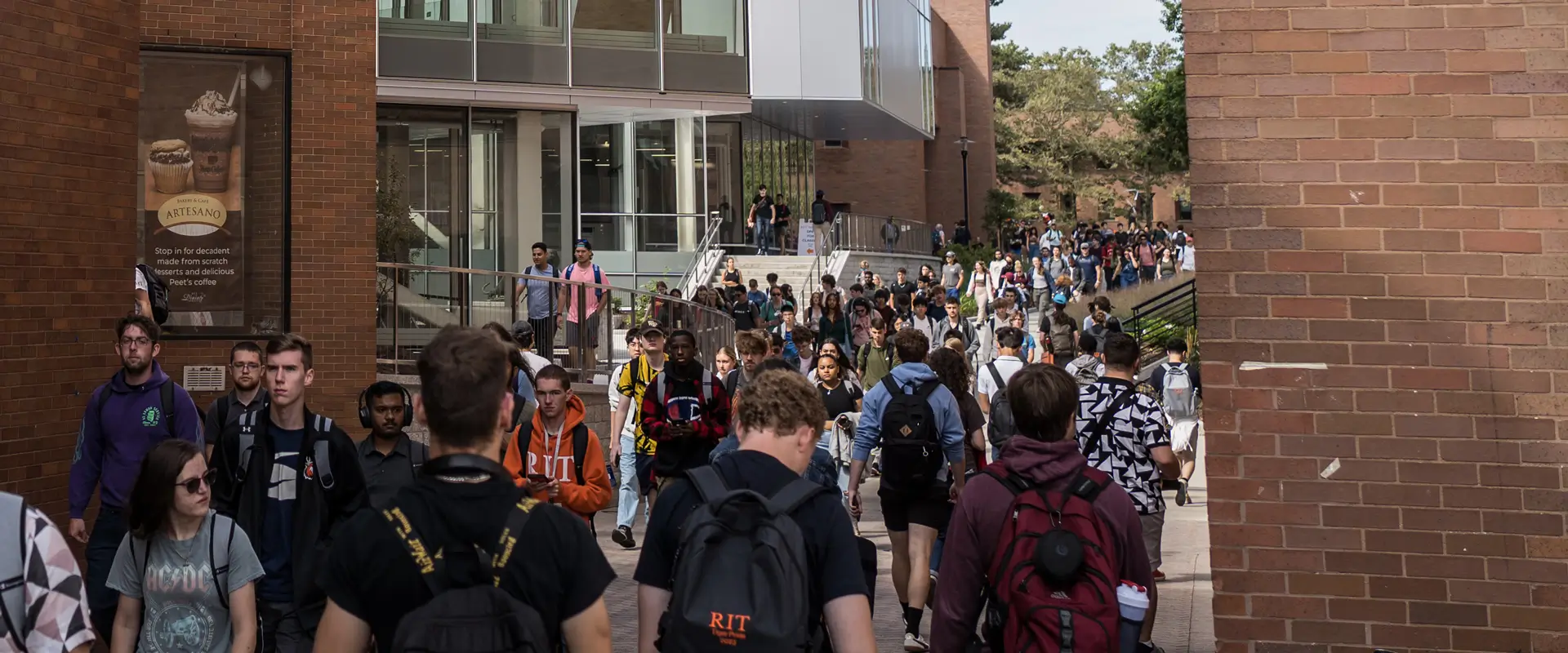 RIT Students walking between buildings that line the Quarter Mile walkway on campus.