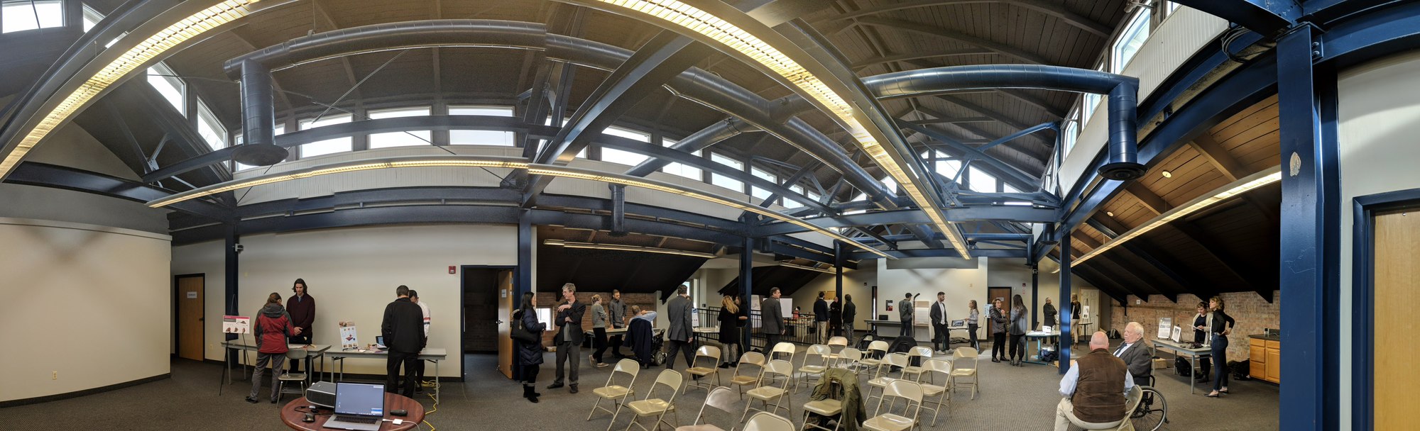 Wide photo of people socializing in conference hall.