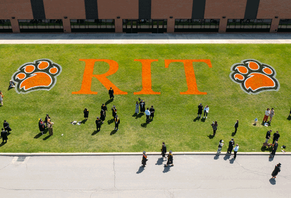 aerial vview of lawn with RIT logo in grass and students standing on grass