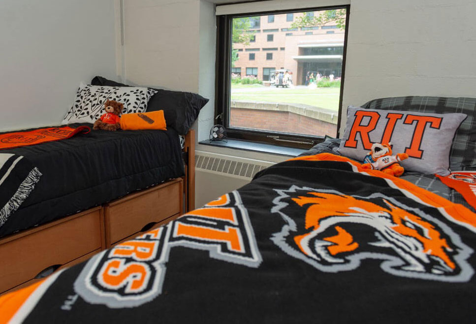 two beds in a dorm room decorated with RIT branded bedding