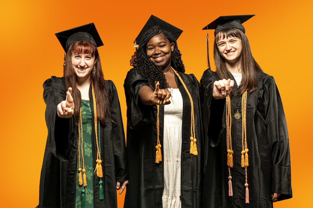 three students in caps and gowns spelling R I T in A S L
