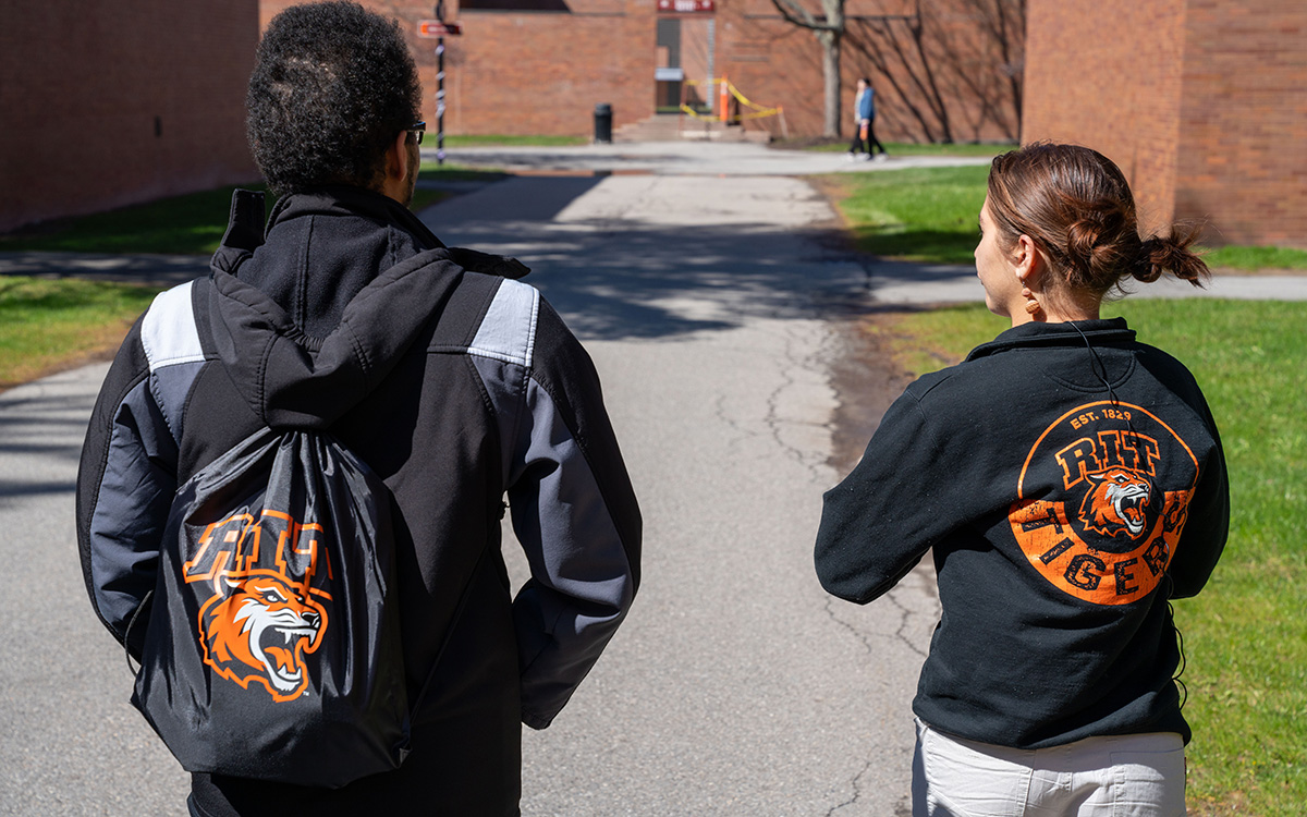 student giving a tour to a family with a R I T jacket on from the back