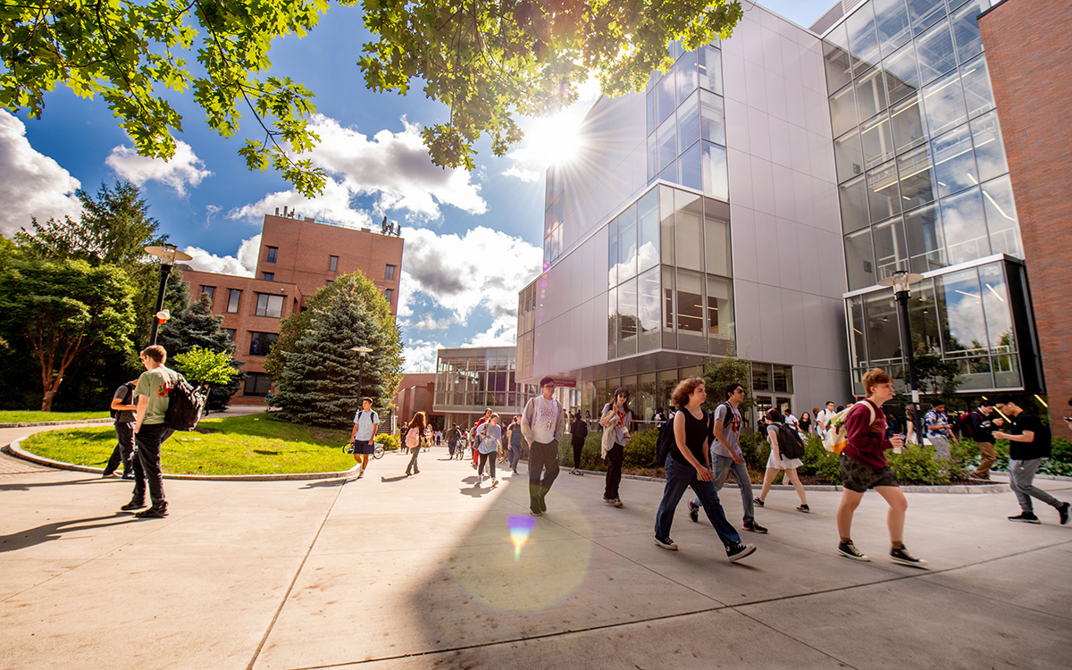 Students walking on campus with the sun shining