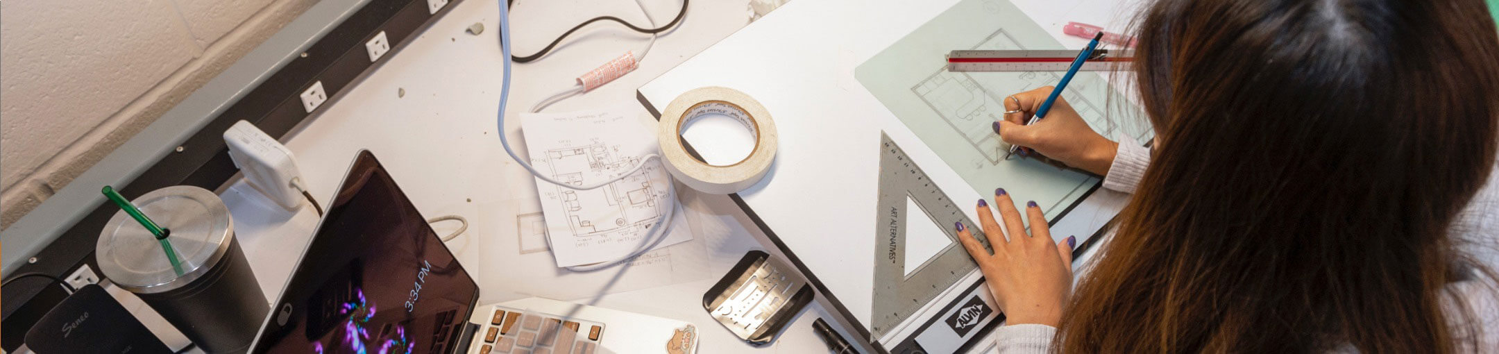 A person sitting at a workbench, working on a design.