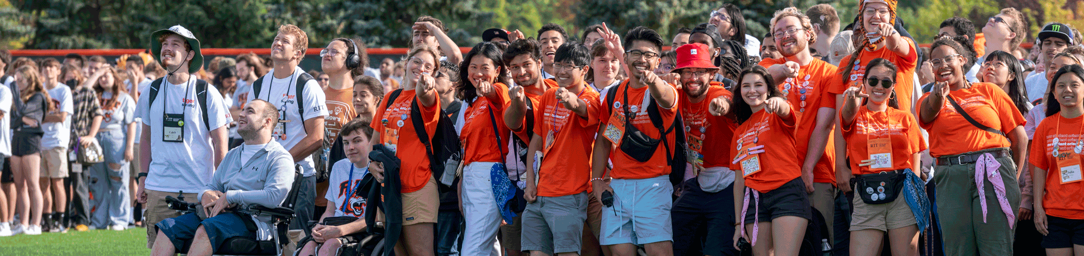 a group of RIT students stand next to each other pointing at the camera and smiling