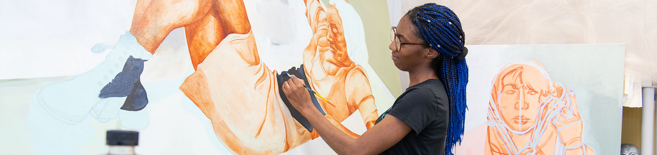 Student painting a mural on a wall