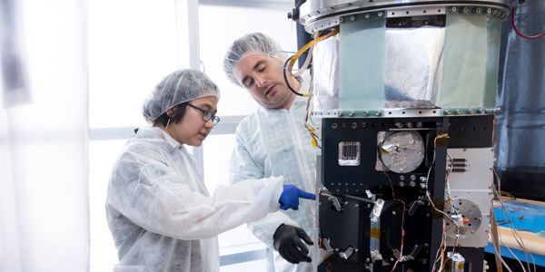 a student and professor inspect a machine