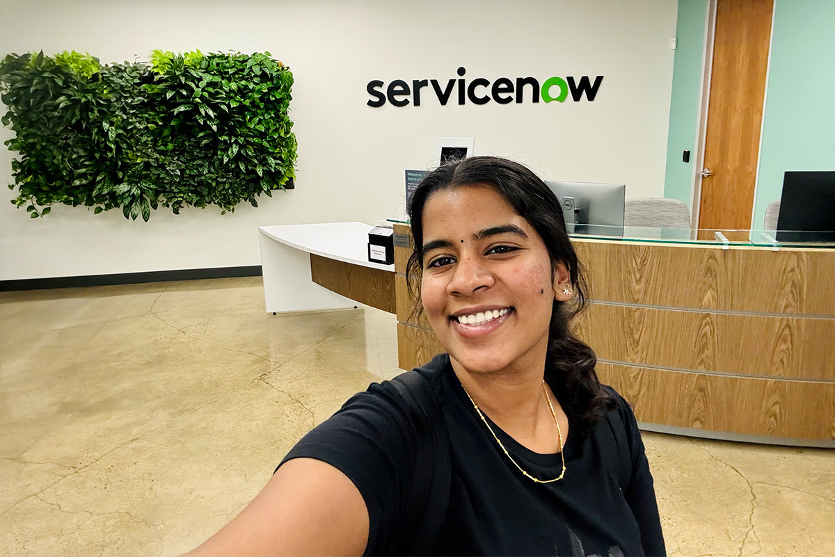 an RIT student stands in front of a ServiceNow sign