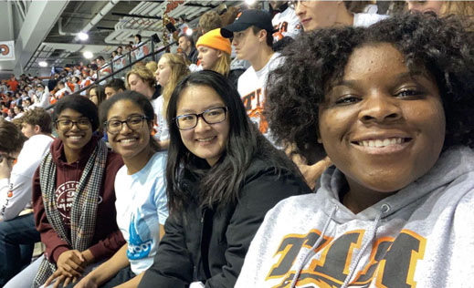 a group of four students sit together at a hockey game