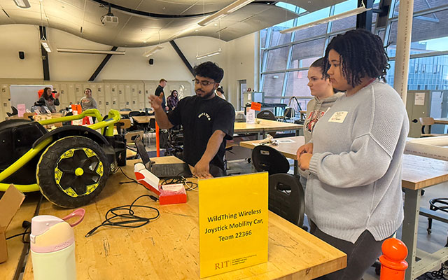 three students working together on a car