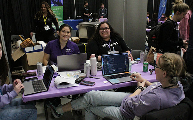 four students typing on their computers at a hackathon
