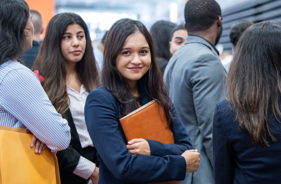 R I T students standing in line to speak with a company representative at a career fair.