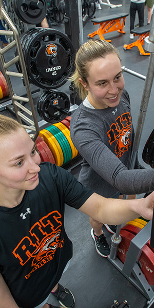 Two students using a weight machine