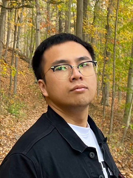 student portrait in front of fall trees