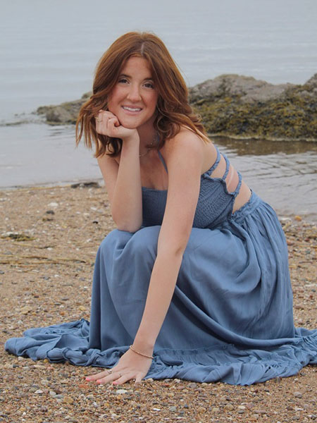 Photo of student in a blue dress on a beach