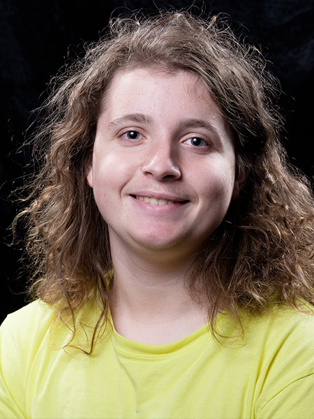 student portrait on a black background wearing a yellow shirt