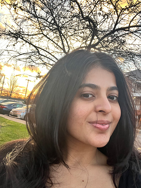 selfie of student in front of trees and a sunset
