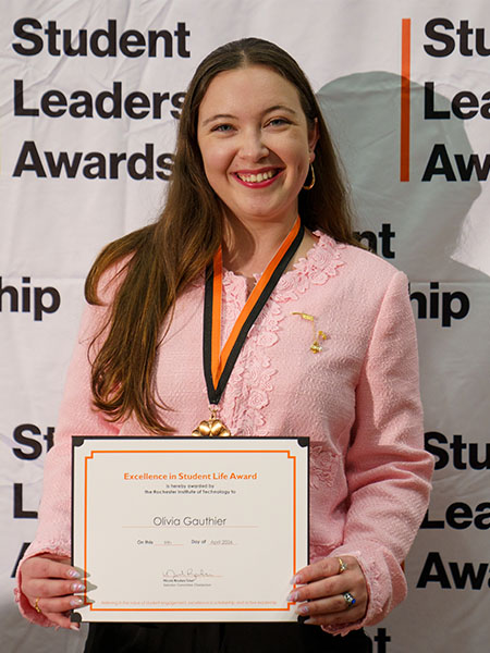 student holding a certificate in front of a backdrop that says "Student Leadership Awards"