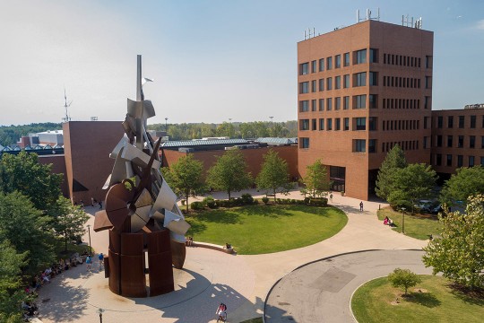 exterior view of seven-floor brick building and metal sculpture.