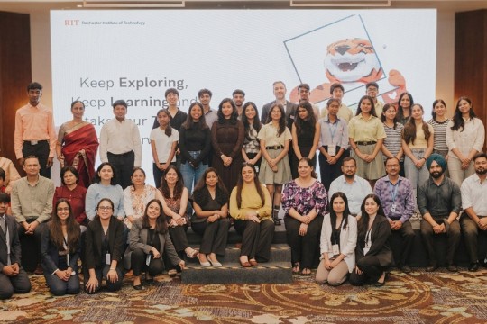 a large group of students and educators stand in a conference hall beneath a presentation for TIGER STRIPES