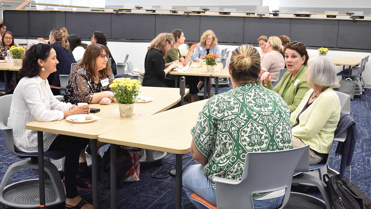 small groups of faculty members seated at tables, having a discussion.