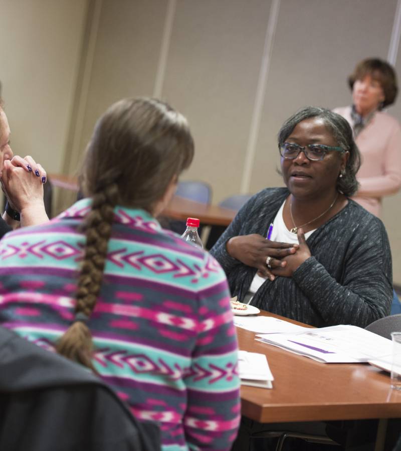 Two women talking with one another across the table from each other.