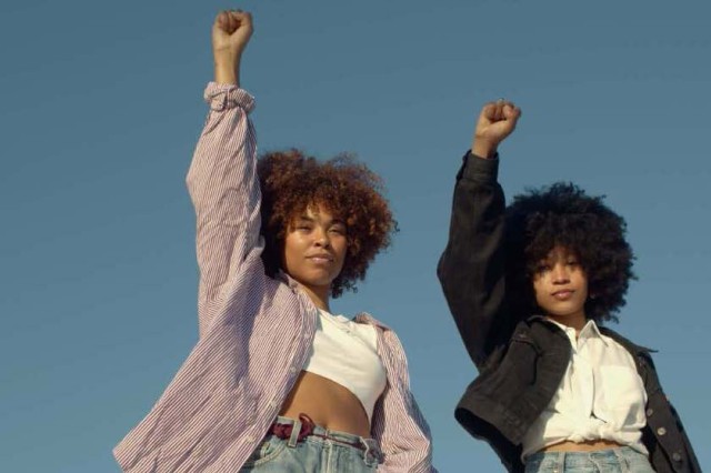 two Black women with their fists raised in the air.